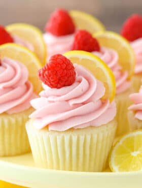Close up of a lemon raspberry cupcake on a yellow cake plate.
