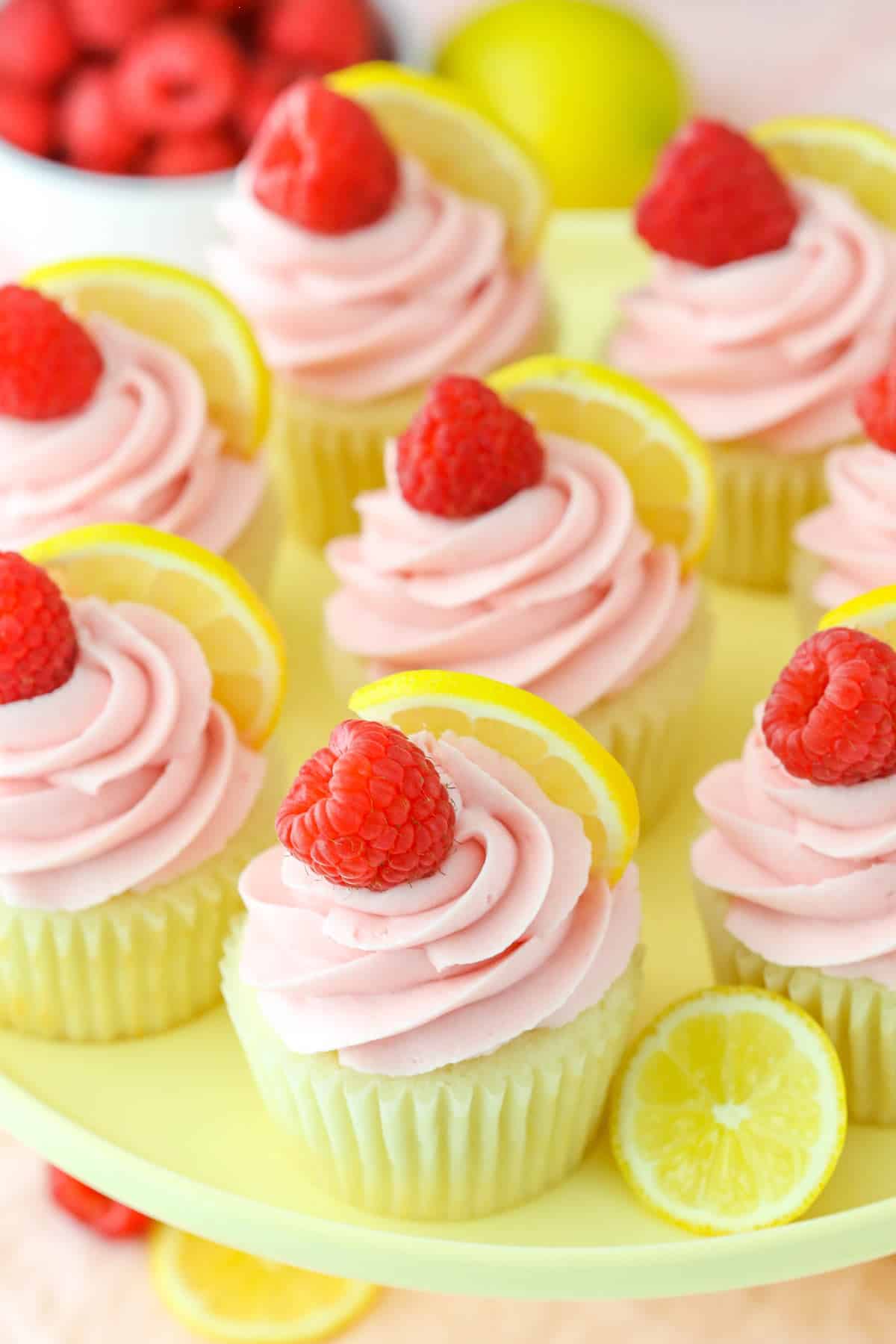 Top view of lemon raspberry cupcakes on a yellow cake plate.