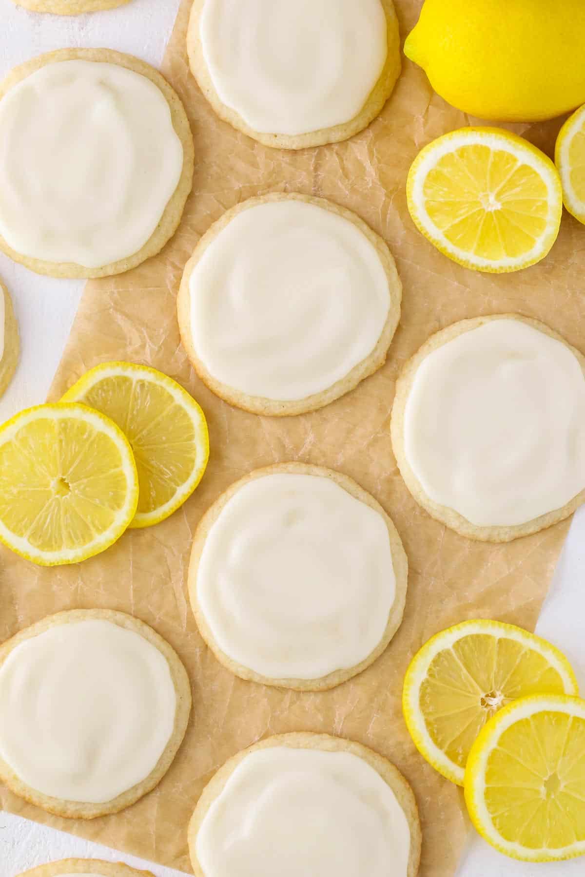 Top view of spaced out Limoncello Cookies and lemon slices on parchment paper.