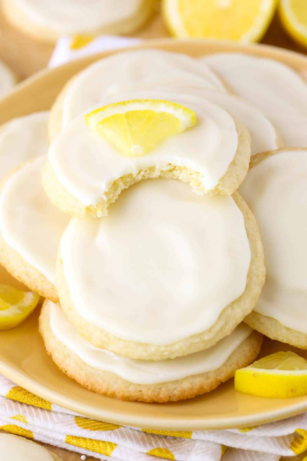 A plate of Limoncello Cookies with a bite taken out of the top cookie.