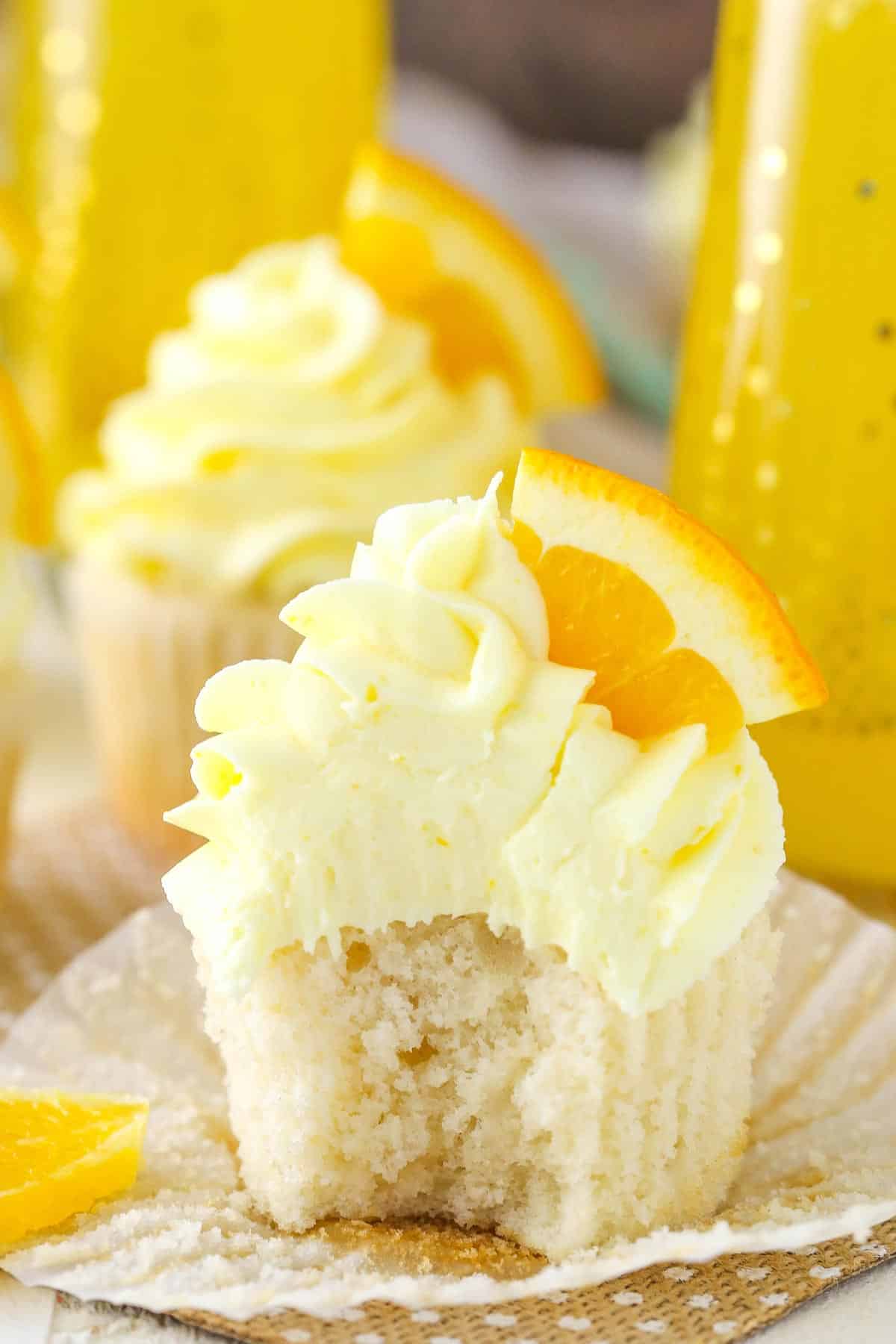 A mimosa cupcake with the wrapper peeled and bite taken out of it.