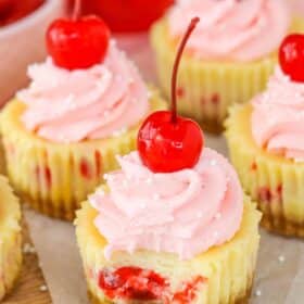 Close up of a mini cherry almond cheesecake with a bite taken out of it.