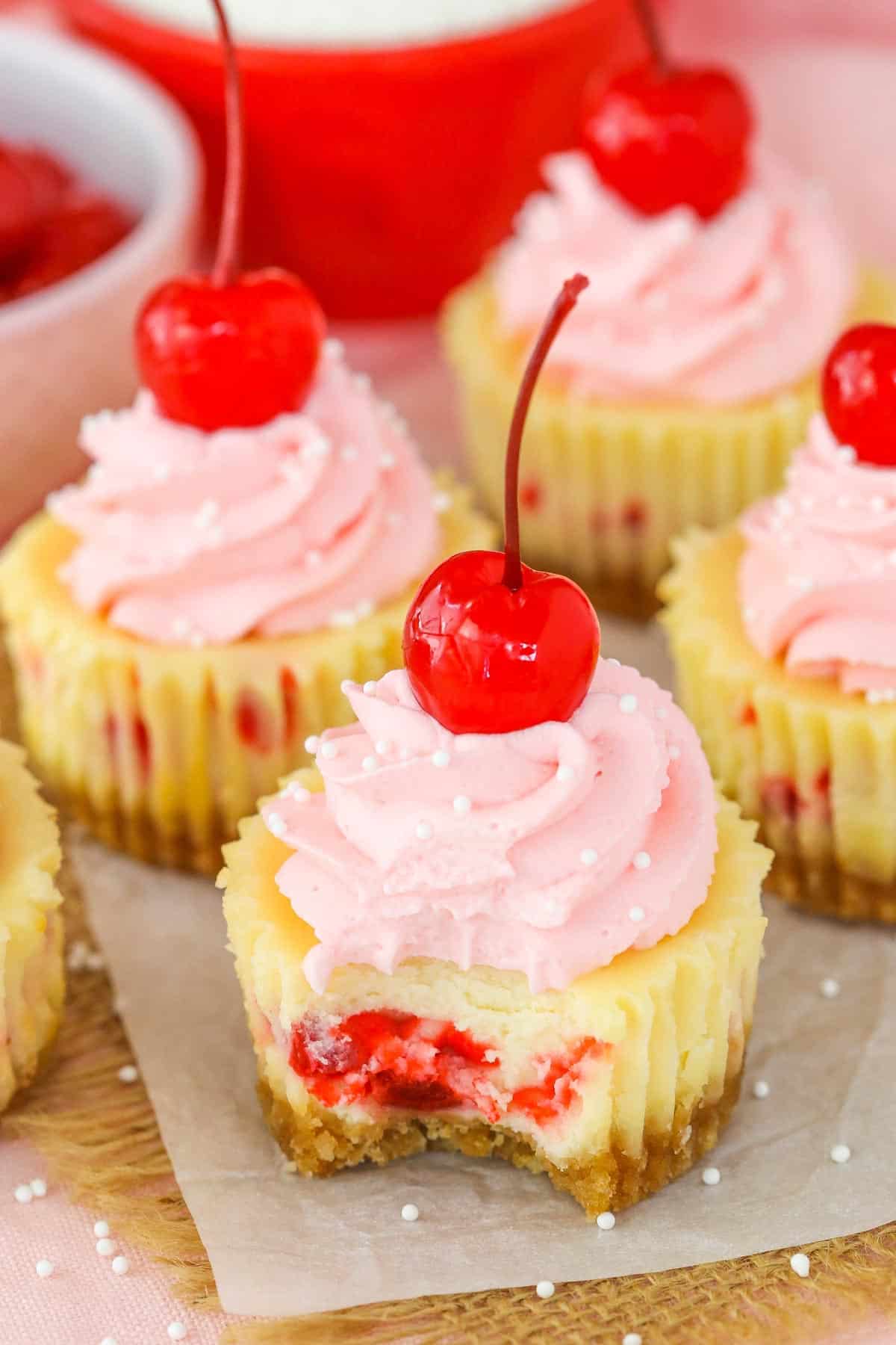 Close up of a mini cherry almond cheesecake with a bite taken out of it.