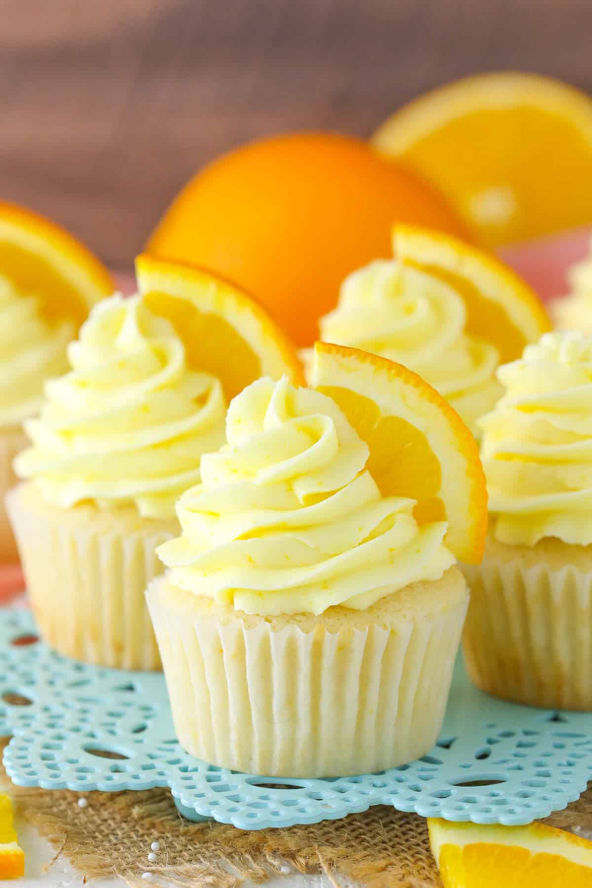 Orange cream cupcakes on a light blue plate.