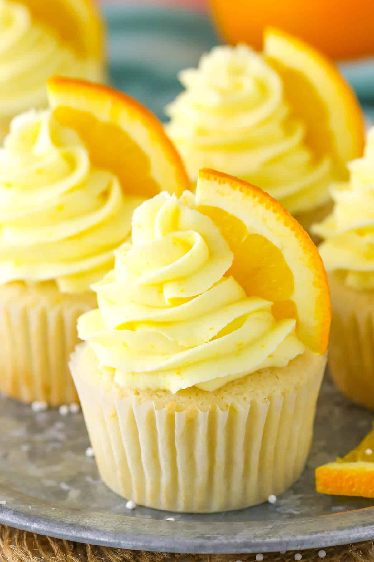 Close up of orange cream cupcakes on a silver tray.