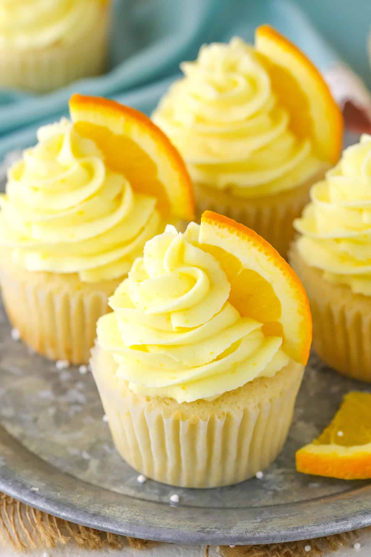 Four orange cream cupcakes on a silver tray.