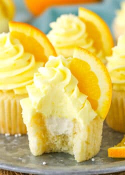 An orange cream cupcake with a bite taken out of it.