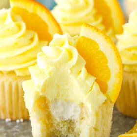 An orange cream cupcake with a bite taken out of it.