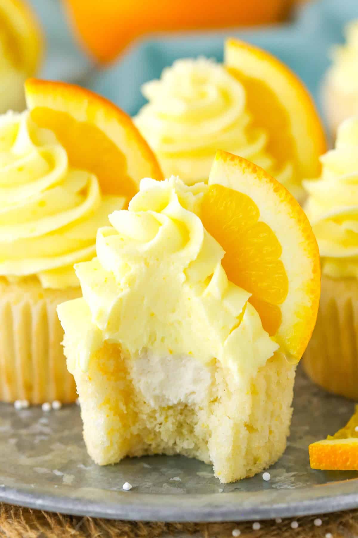 An orange cream cupcake with a bite taken out of it.