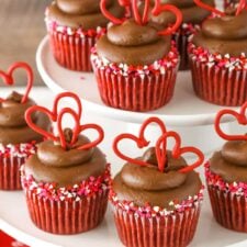 Close up of several rows of red velvet cupcakes on a white tiered cake plate.