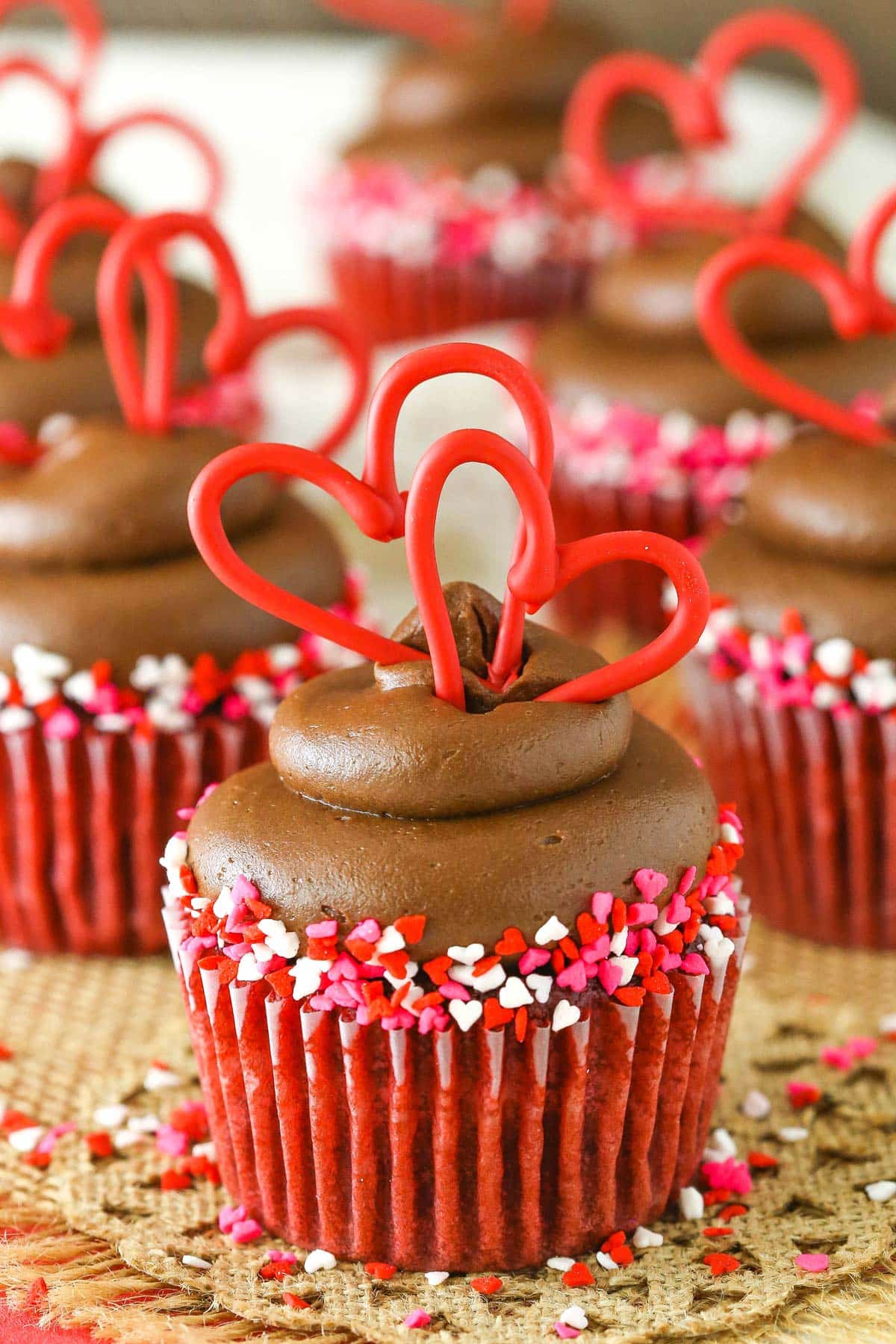 Close up of a red velvet cupcake with chocolate cream cheese frosting on burlap.
