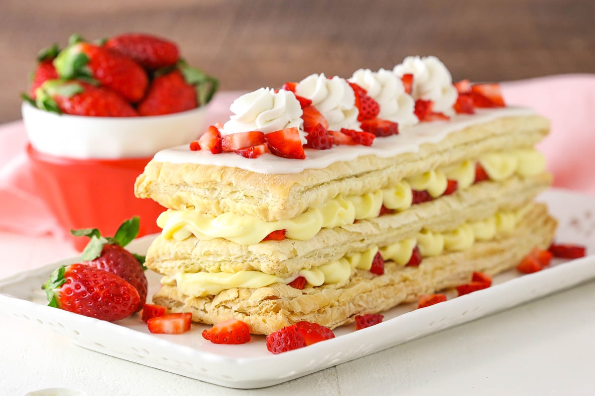 A Strawberry Napoleon on a white serving tray with strawberries in the background.