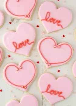 Overhead view of heart-shaped cutout cookies on a white surface.