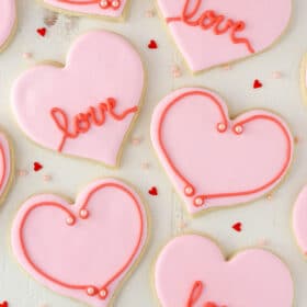 Overhead view of heart-shaped cutout cookies on a white surface.