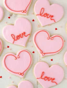 Overhead view of heart-shaped cutout cookies on a white surface.