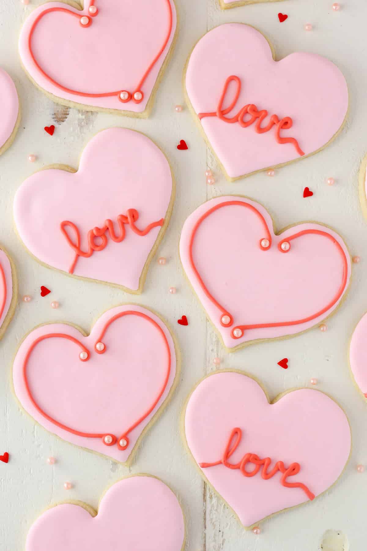 Overhead view of heart-shaped cutout cookies on a white surface.