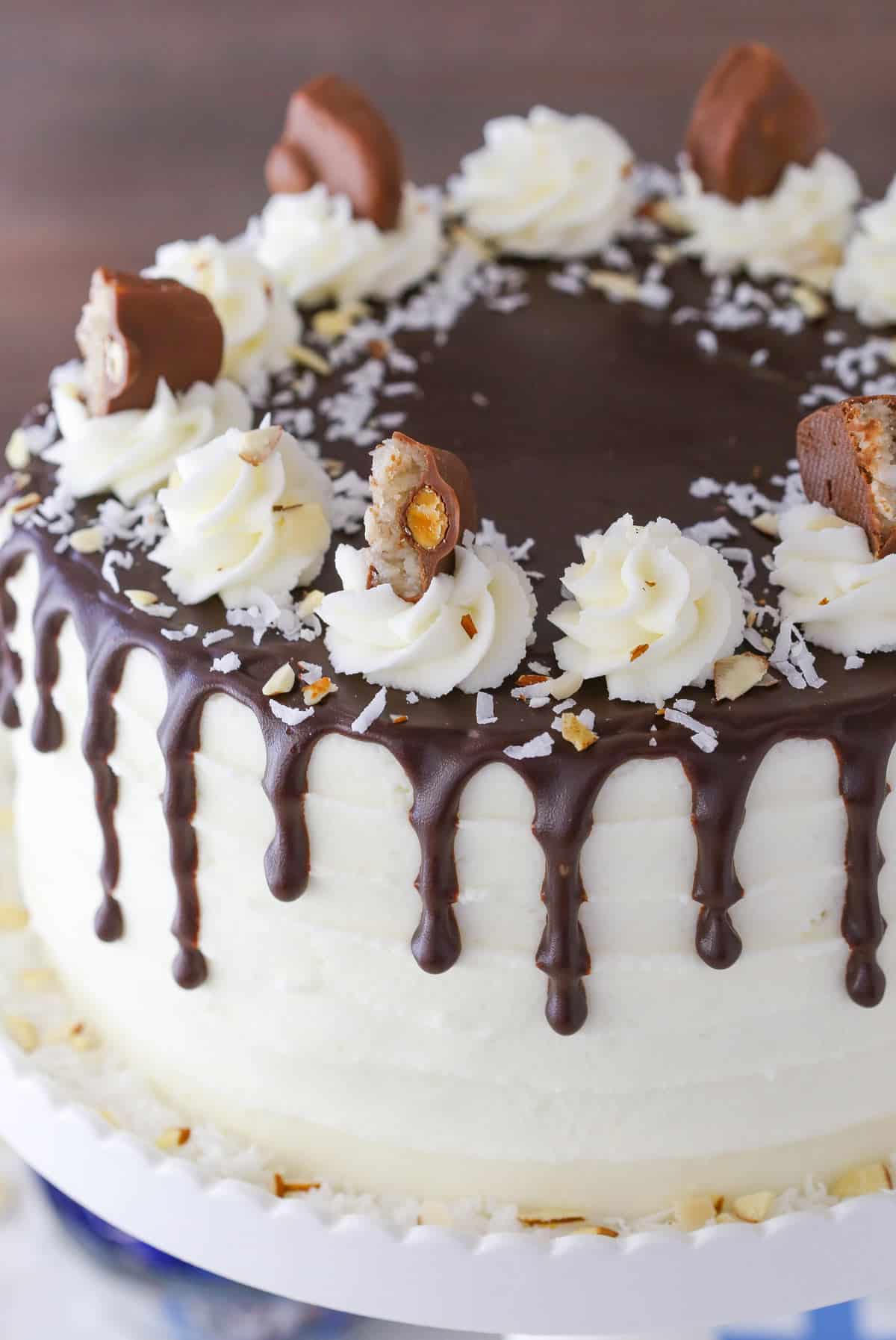An almond joy layer cake on a white cake stand.