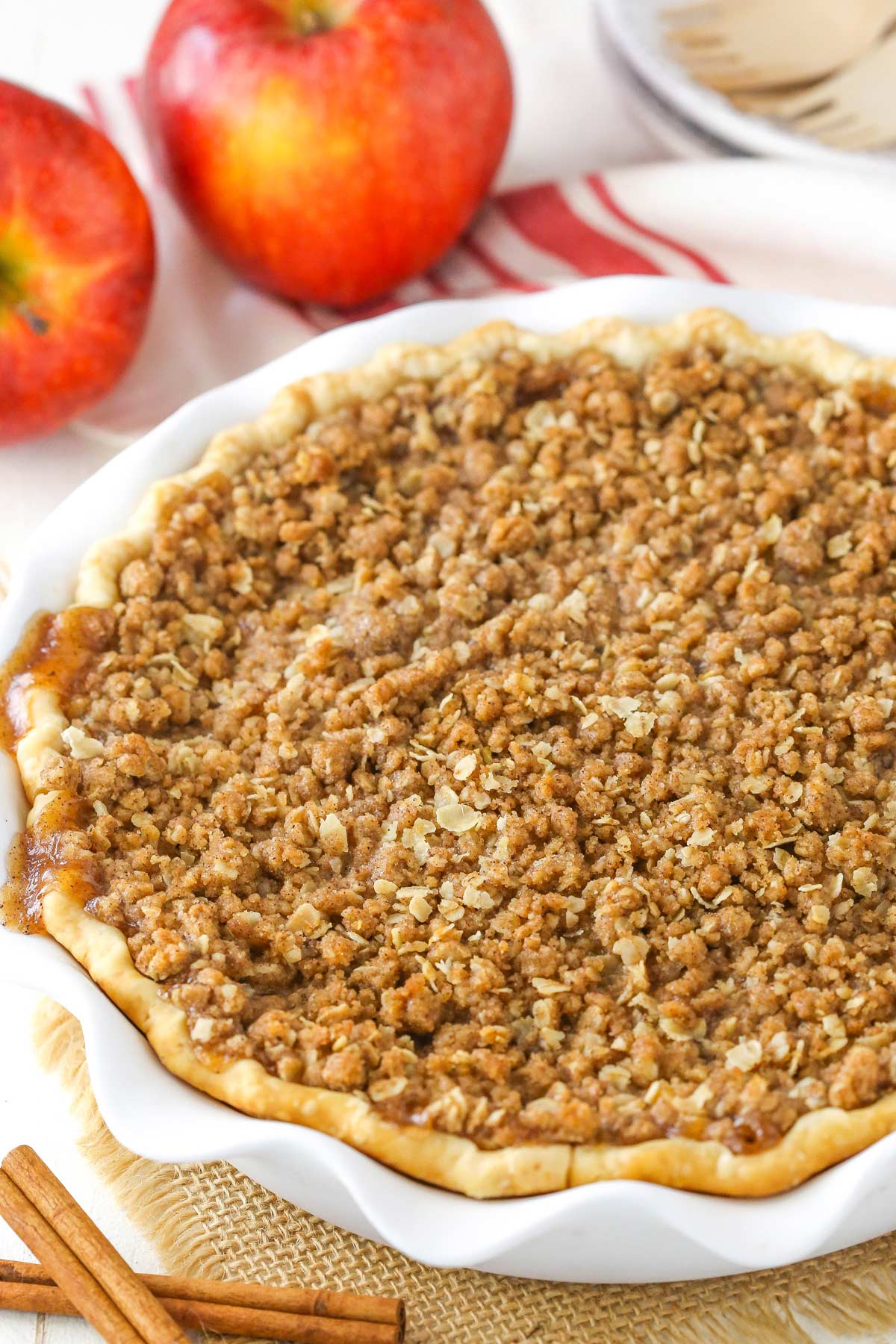 An apple crumb cheesecake pie in a white cake plate.