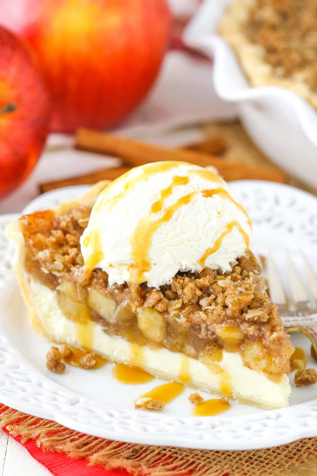 A slice of apple crumb cheesecake pie topped with vanilla ice cream and caramel.