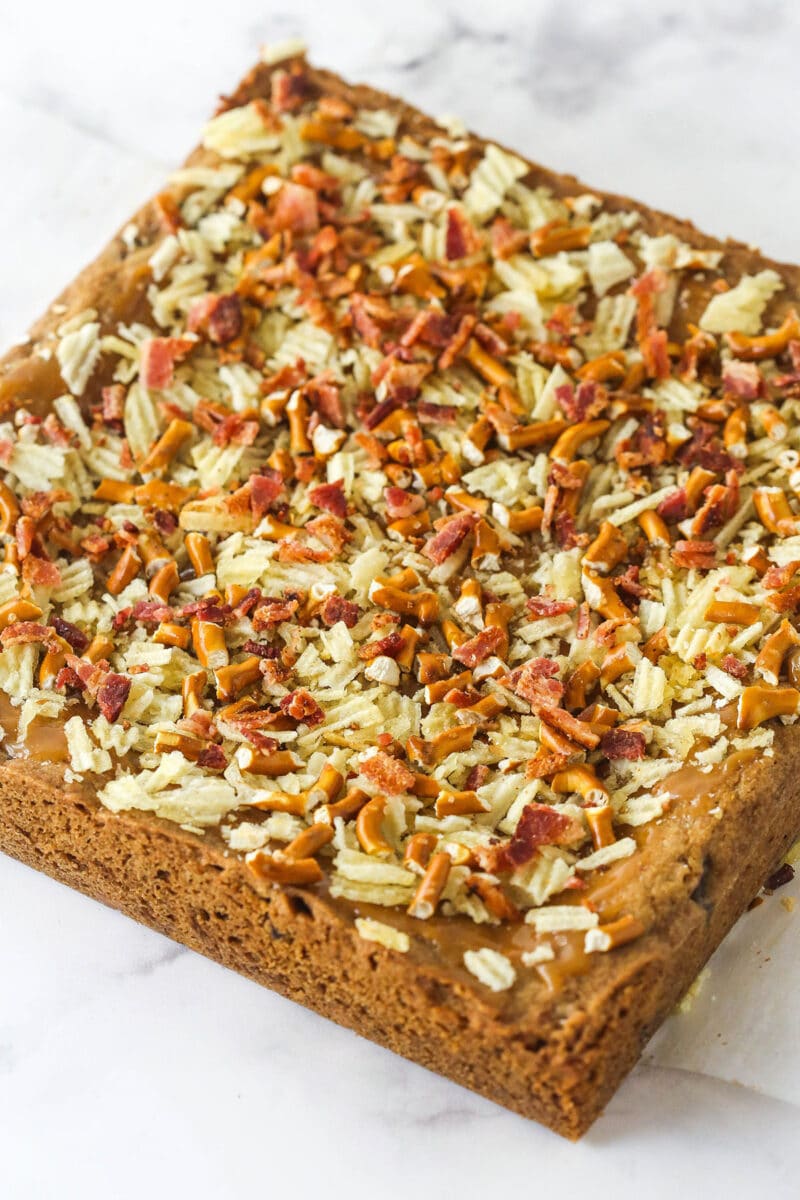cookie bars with chopped chips, bacon and pretzels on top