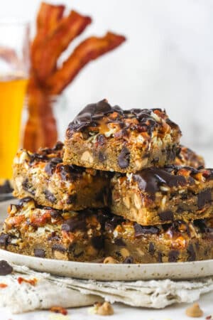 cookie bars piled onto speckled plate with bacon and beer in background