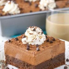 A slice of baileys chocolate mousse brownie cake on a small white plate.