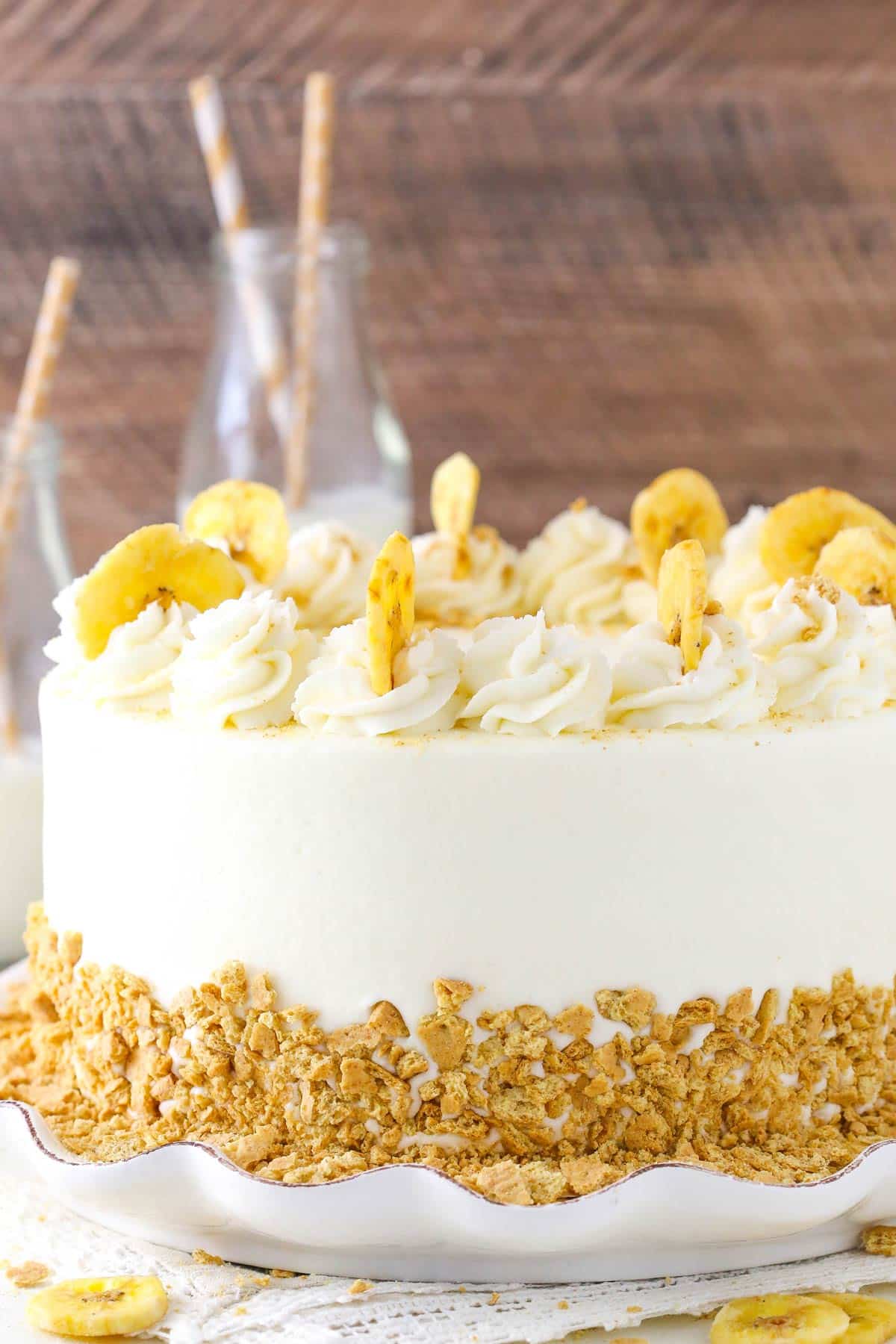 Side view of a banana cream layer cake on a white cake plate.