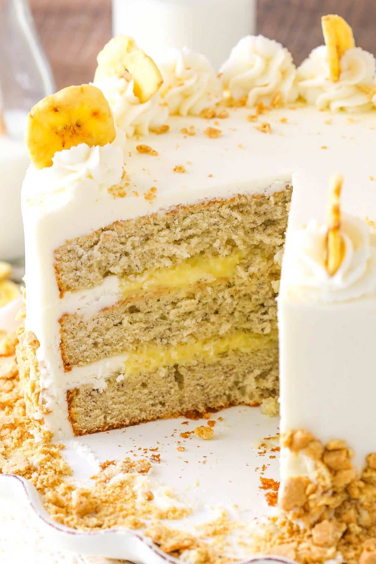 A banana cream layer cake with several slices removed to show inside layers.
