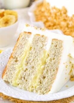 A slice of banana cream layer cake on a small white plate.
