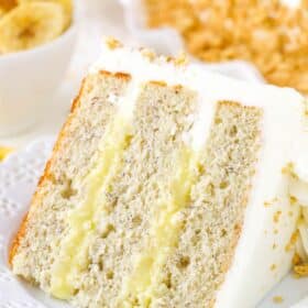 A slice of banana cream layer cake on a small white plate.