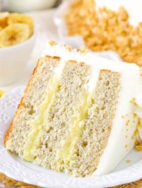 A slice of banana cream layer cake on a small white plate.