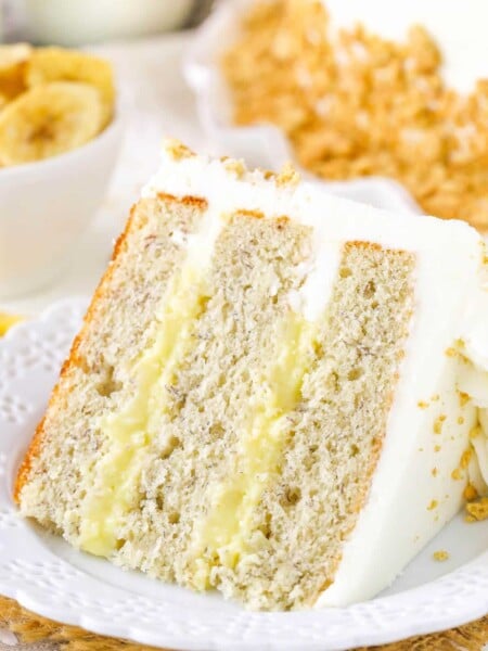 A slice of banana cream layer cake on a small white plate.