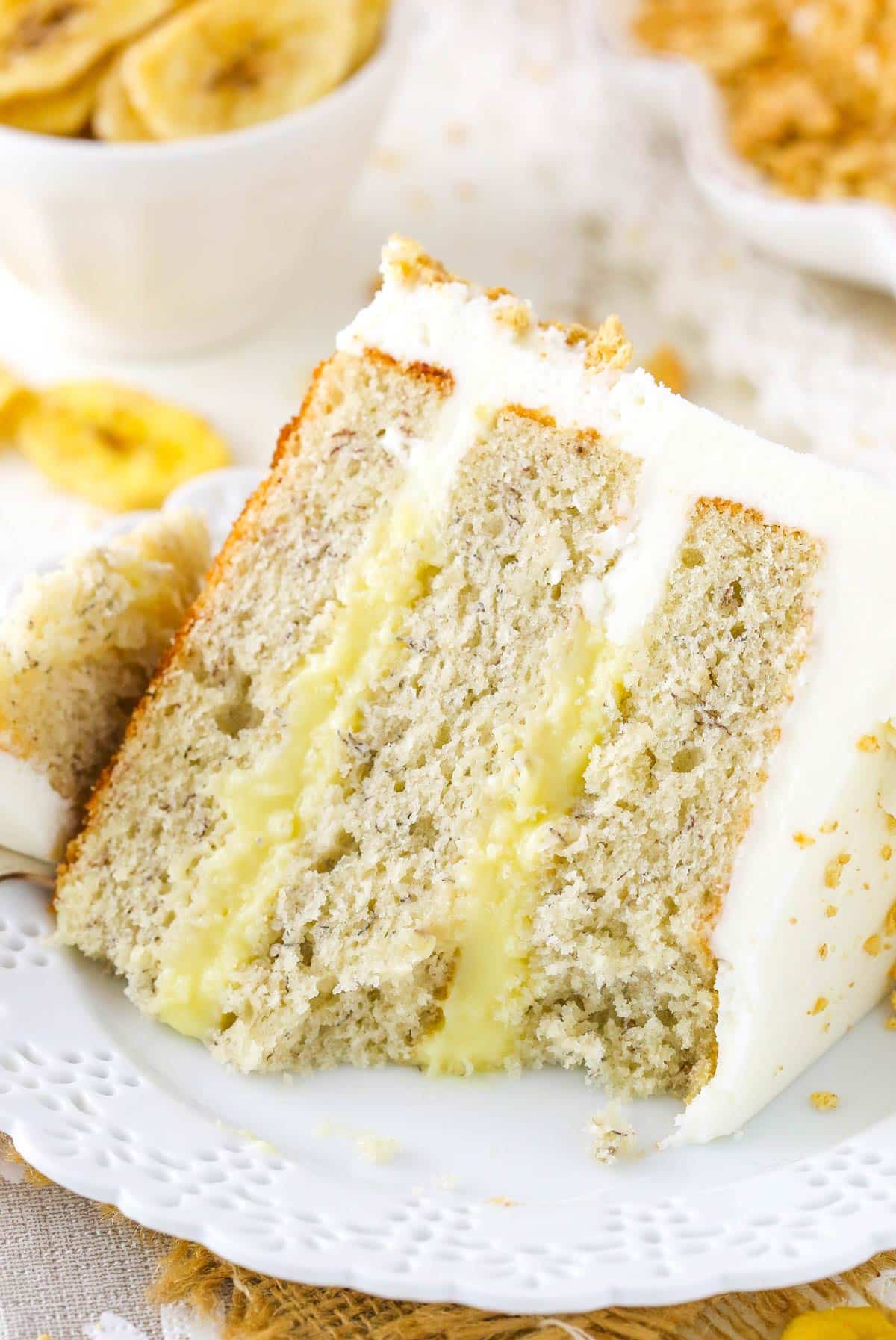 A slice of banana cream layer cake with a few bites removed.