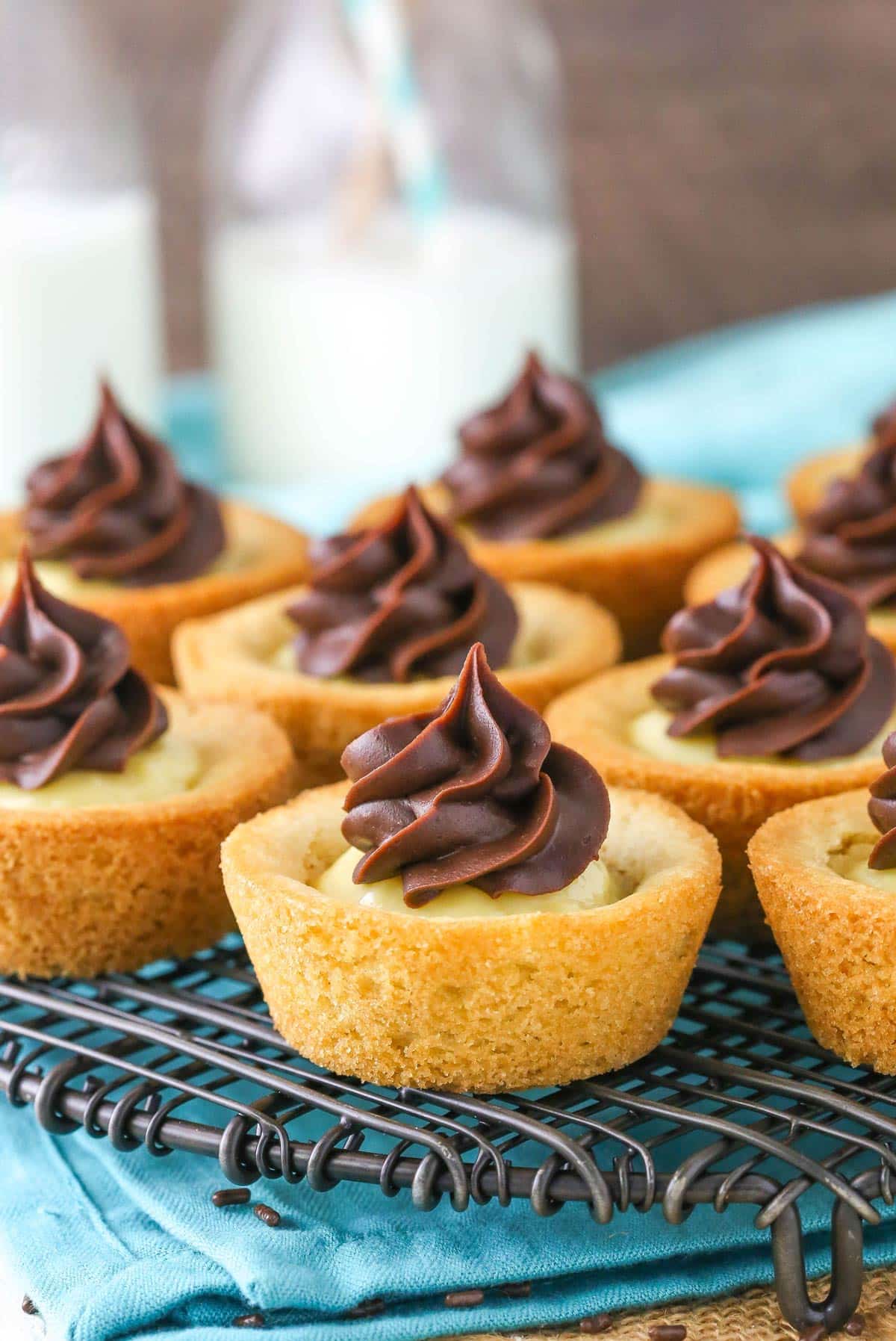 Several boston cream pie cookie cups on a metal rack.