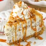 A slice of browned butter pecan cheesecake drizzled with caramel sauce.