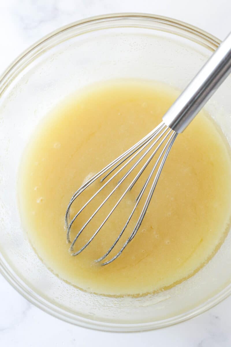 These moist, chewy Brownie Bites are so easy to make and WAY better than the ones you can get at the store. Try to eat just one. I dare you. Whisking together the butter, oil, sugar, and vanilla for brownie batter.