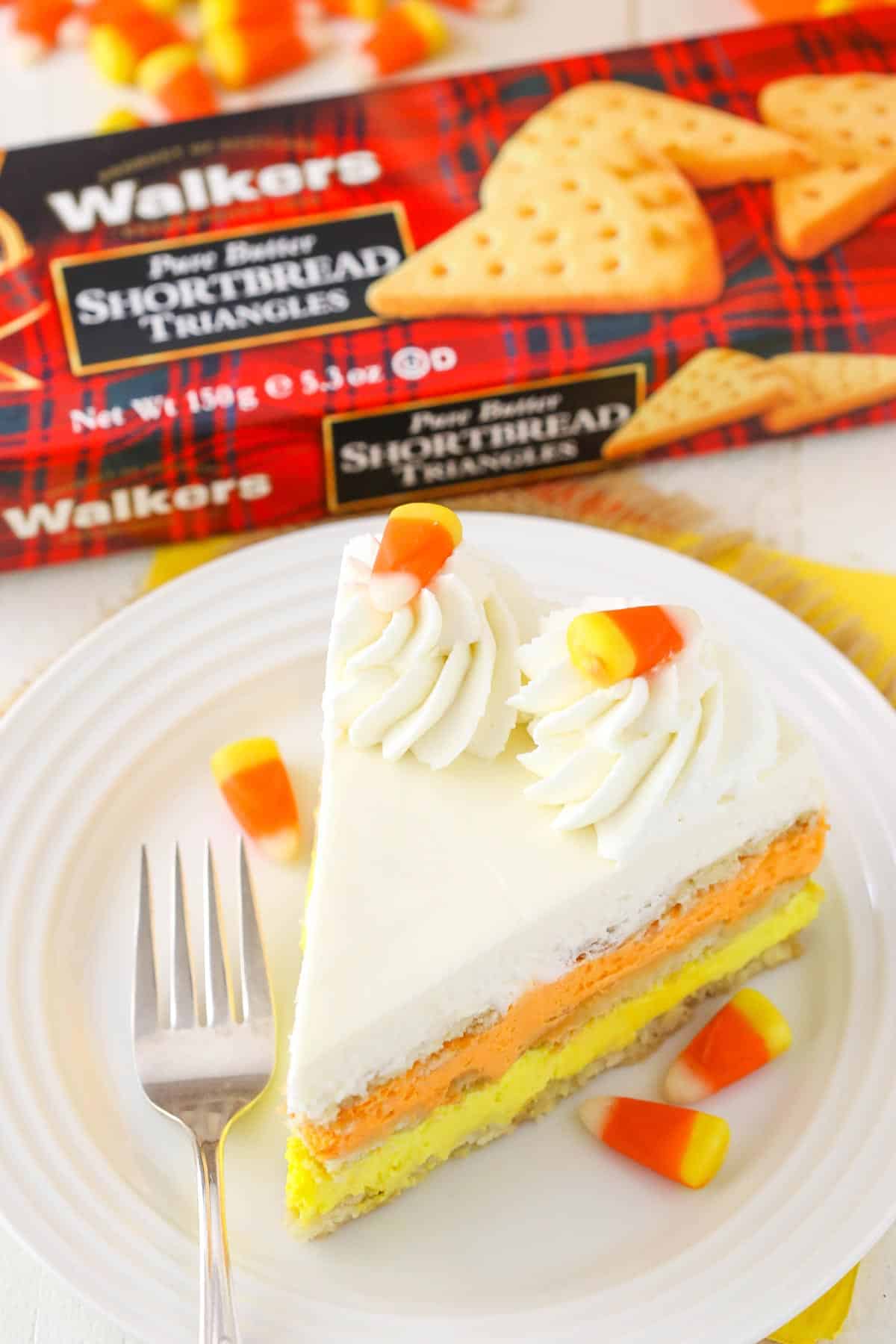 A slice of candy corn icebox cake next to a box of shortbread cookies.