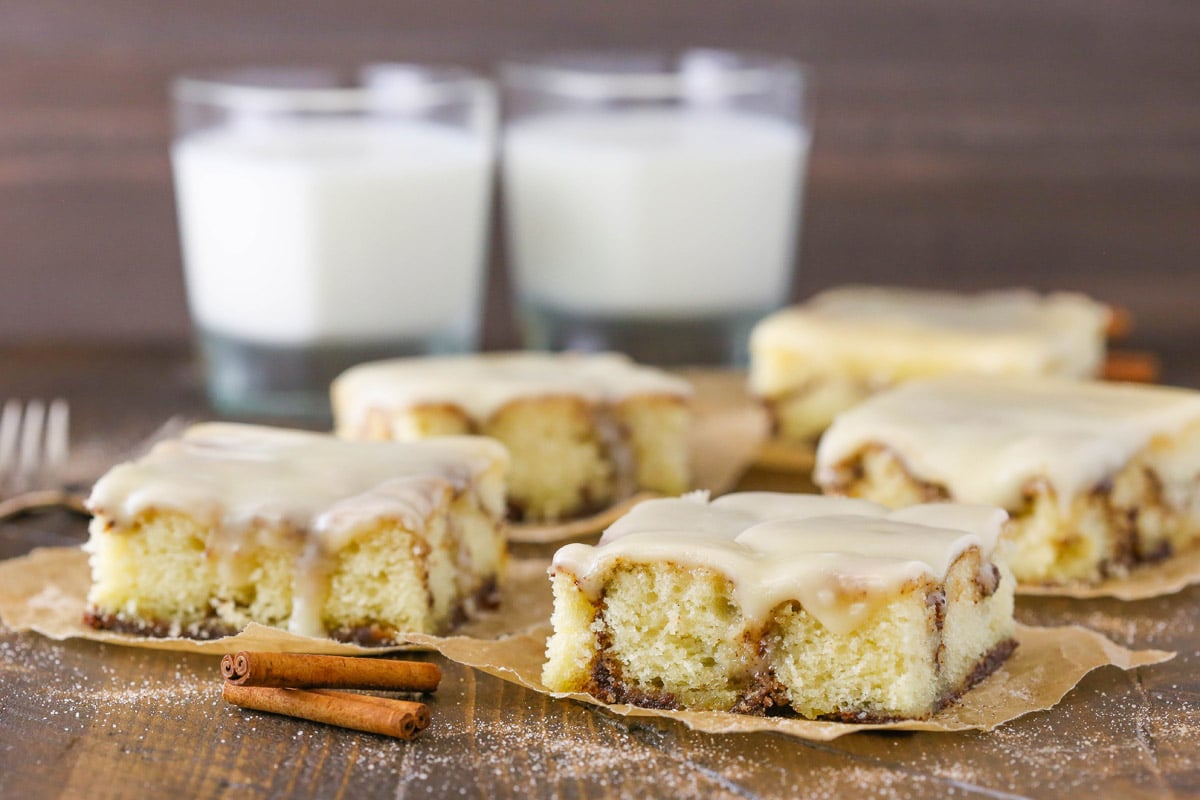 Side view of slices of cinnamon roll snack cake on parchment squares.