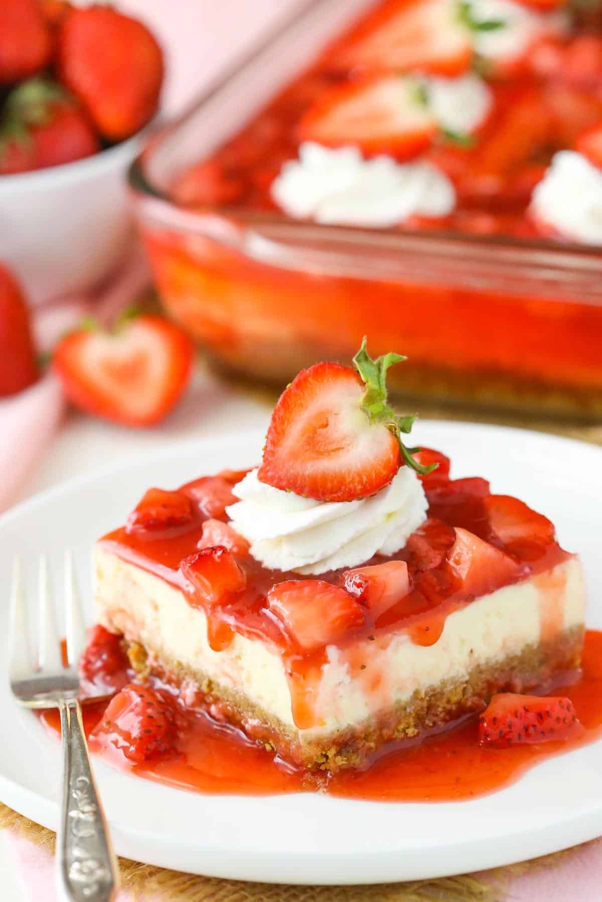 A slice of strawberry cheesecake on a white plate.