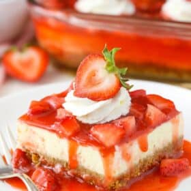 A slice of strawberry cheesecake on a small white plate.
