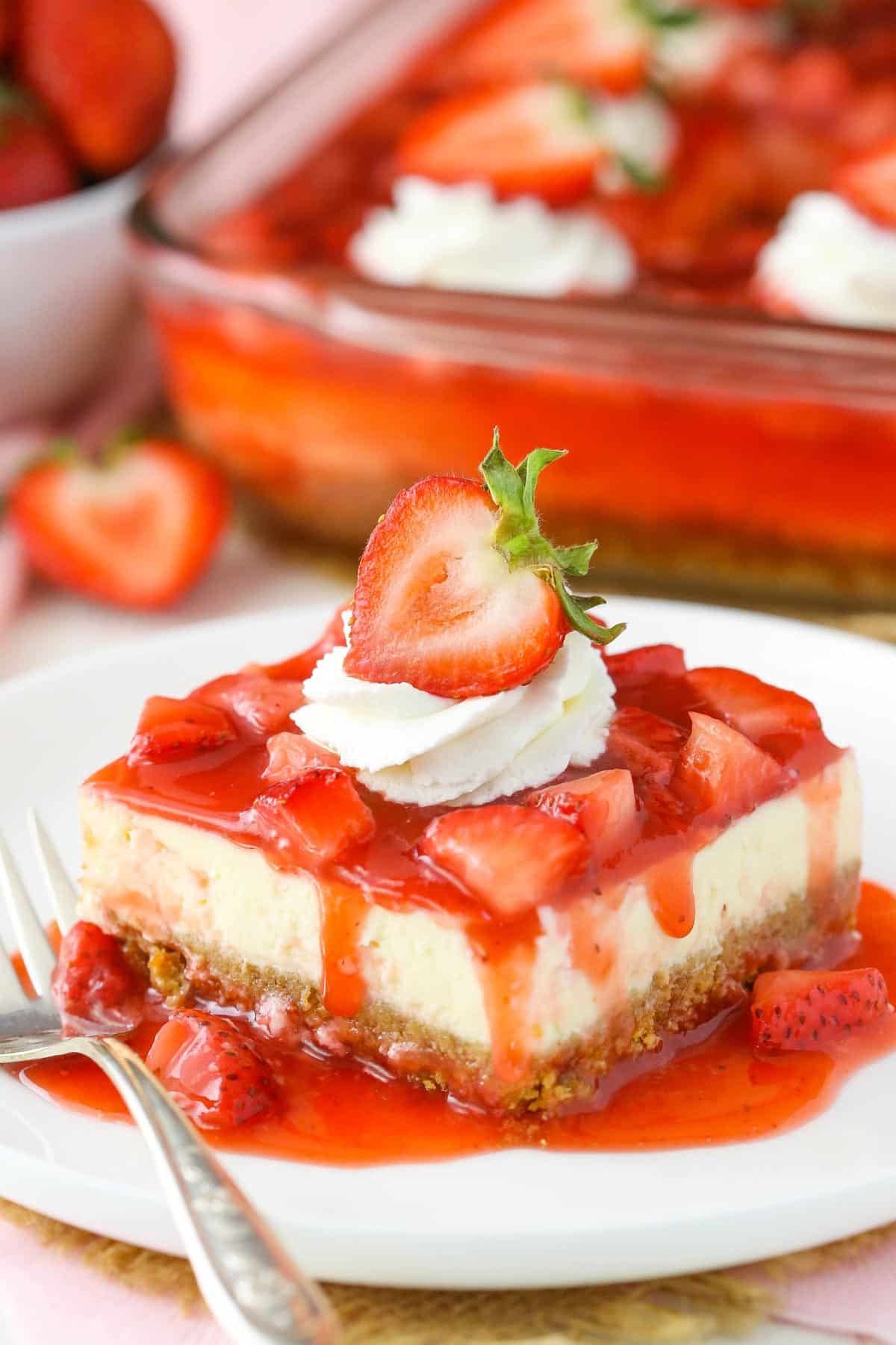 A slice of strawberry cheesecake on a small white plate.