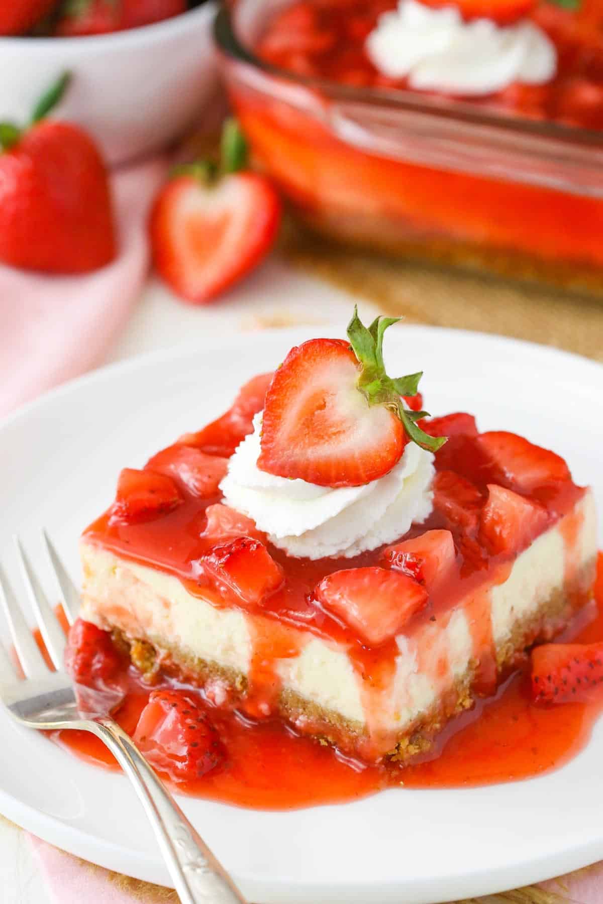 A slice of strawberry cheesecake on a white plate.