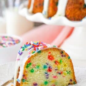 A slice of funfetti bundt cake on a white plate.