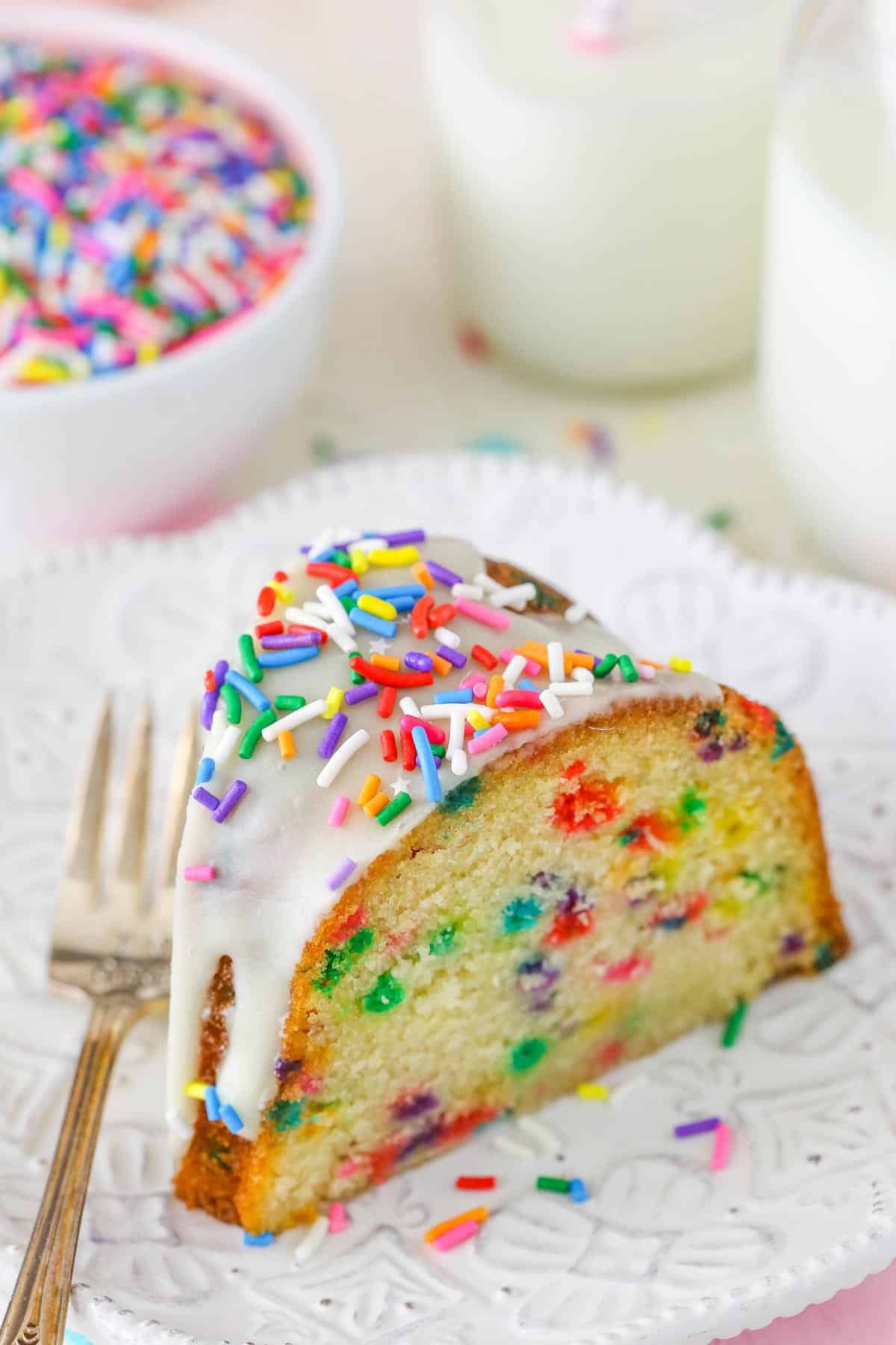 A slice of funfetti bundt cake on a white plate.