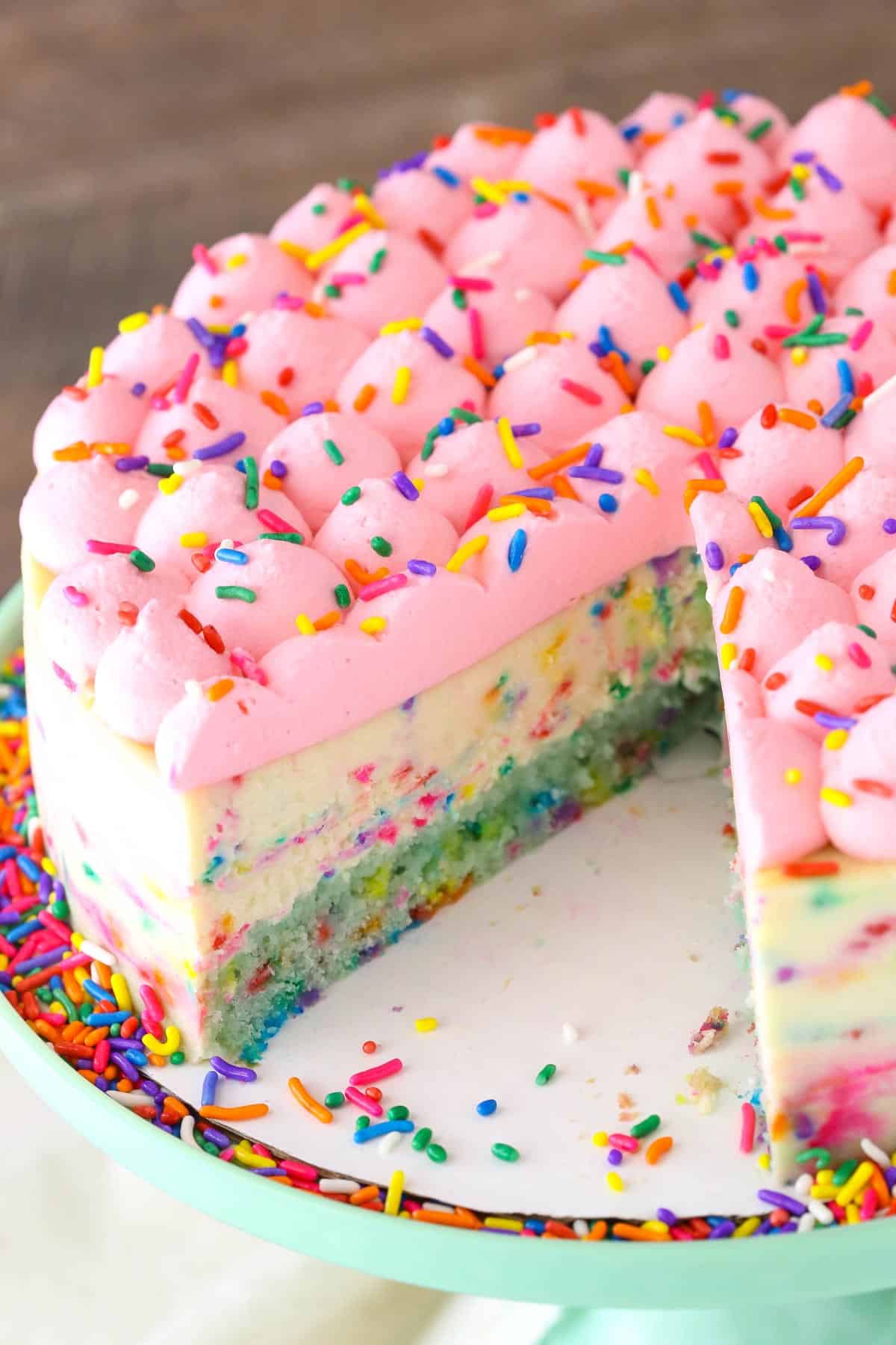 A funfetti cheesecake with cake bottom with a few slices removed.