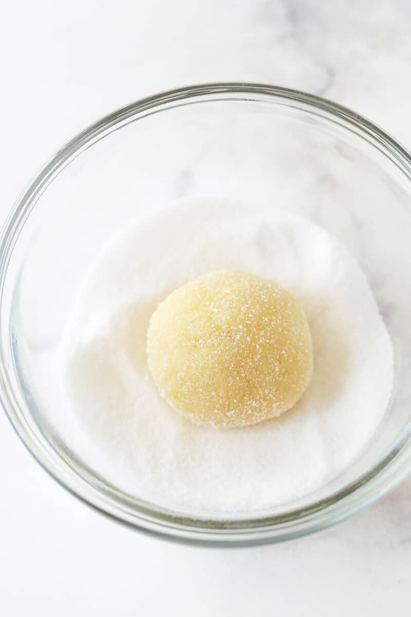 Rolling a ball of lemon cookie dough in sugar.
