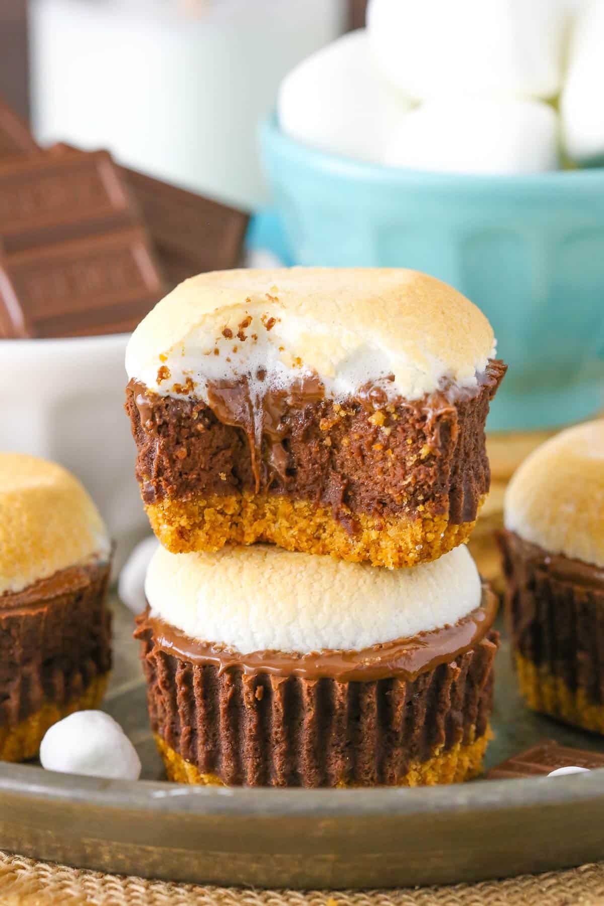Two mini s'mores cheesecakes stacked on top of each other with a bite removed from the top cake.