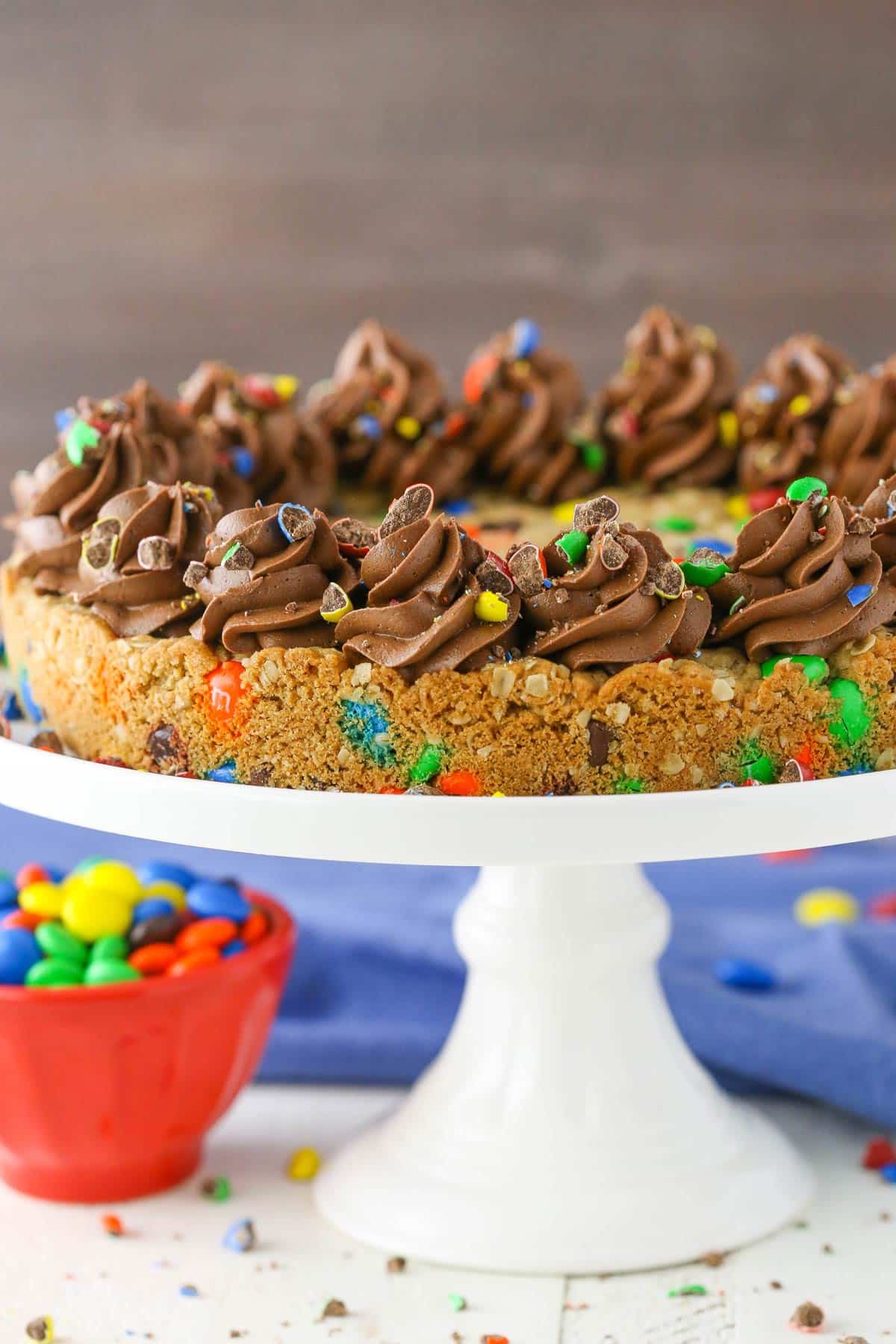 Side view of a monster cookie cake on a white cake plate.