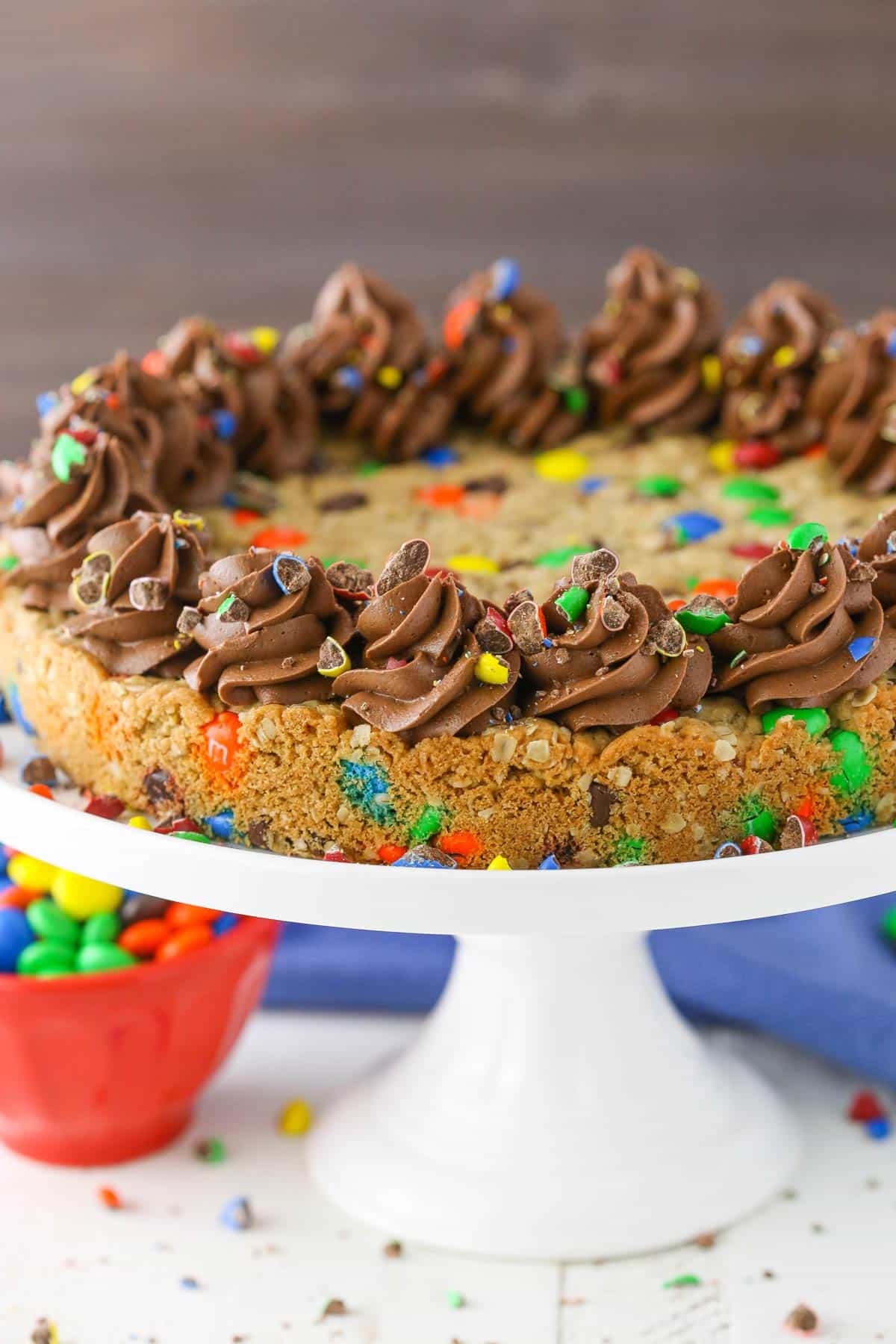 Side view of a monster cookie cake on a white cake stand.