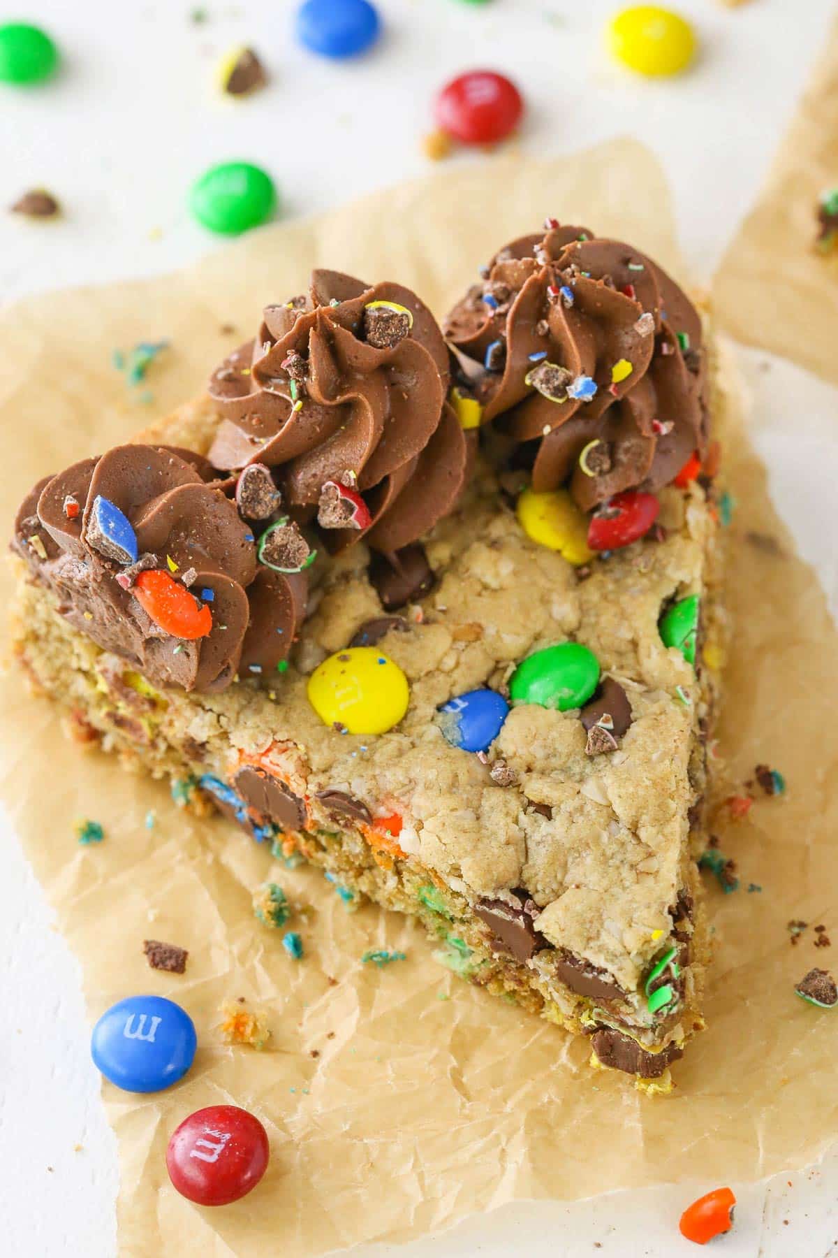 Top view of a slice of monster cookie cake on a piece of parchment paper.